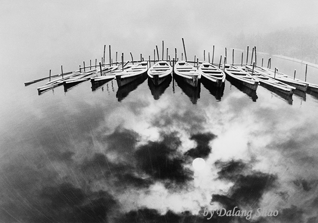 Several boats floating on water that reflects the sky